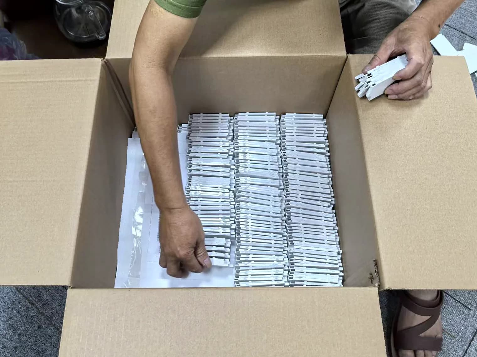 A worker packing components into a carton